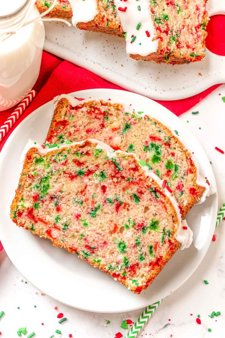 two slices of christmas quick bread on a white plate.