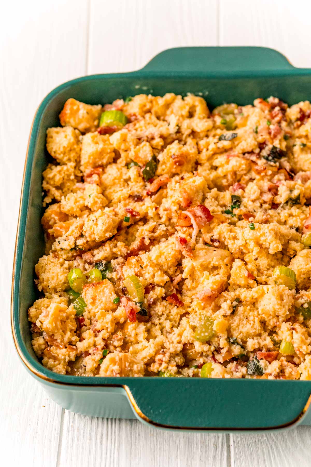 Cornbread stuffing mixture in a teal baking dish ready to be baked.