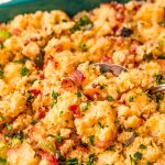Close up photo of cornbread stuffing getting scooped out of a dish.