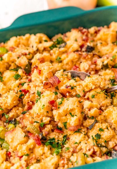 Close up photo of cornbread stuffing getting scooped out of a dish.