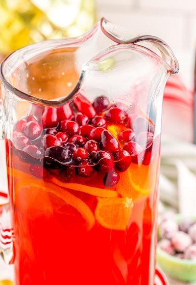 Close up photo of mimosa punch in a pitcher with cranberries.