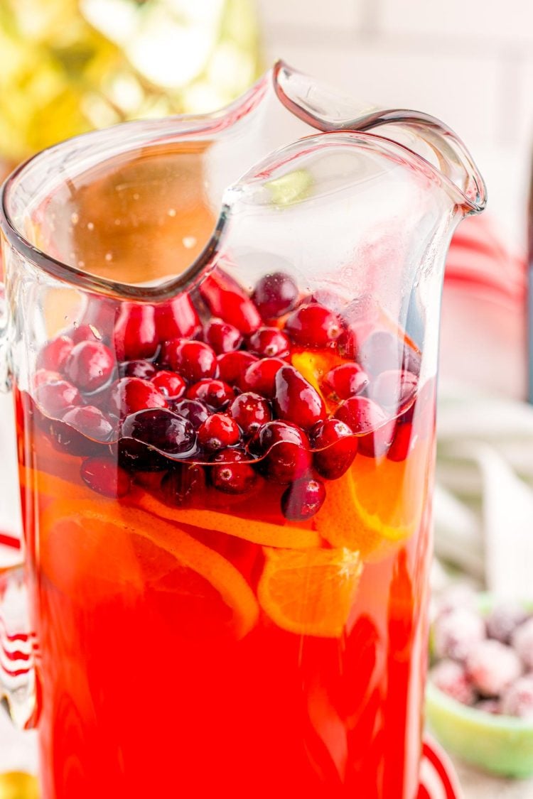 Close up photo of mimosa punch in a pitcher with cranberries.