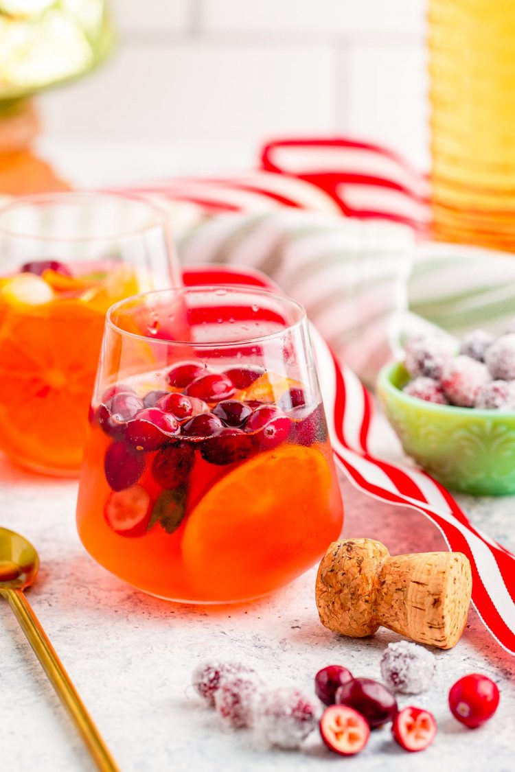 Glass of christmas mimosa punch on a table with holiday decor scattered around.