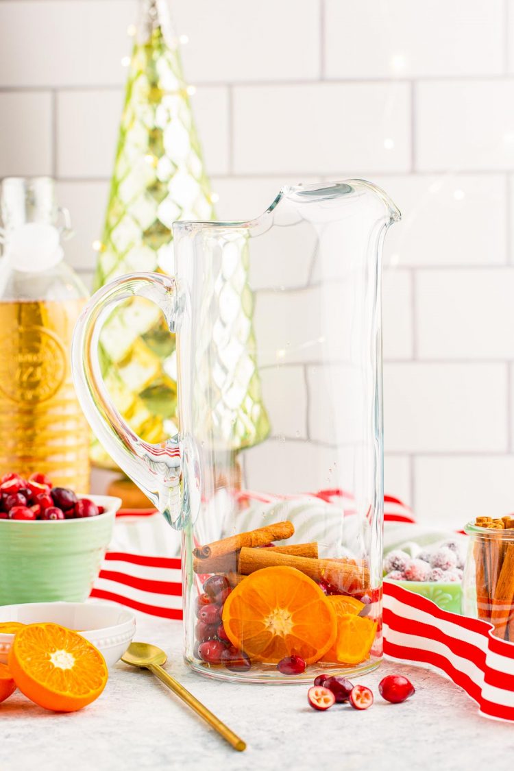 Fruit and cinnamon sticks in a pitcher to make punch.