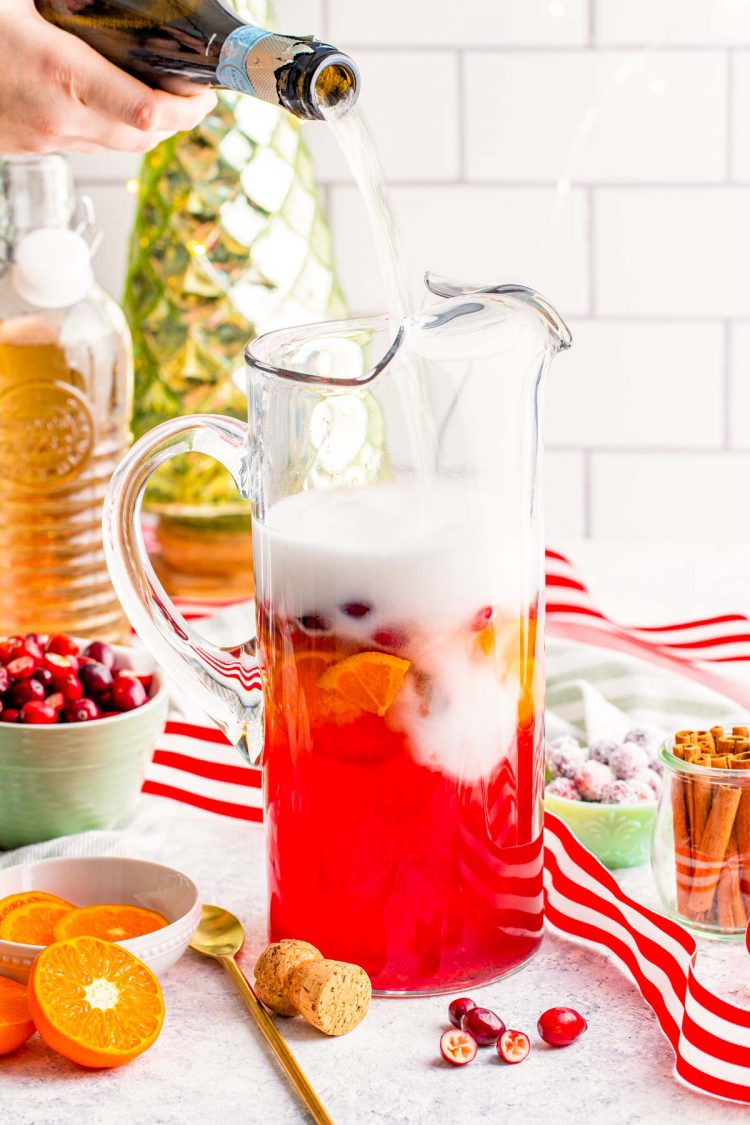 Prosecco being added to a pitcher to make punch.