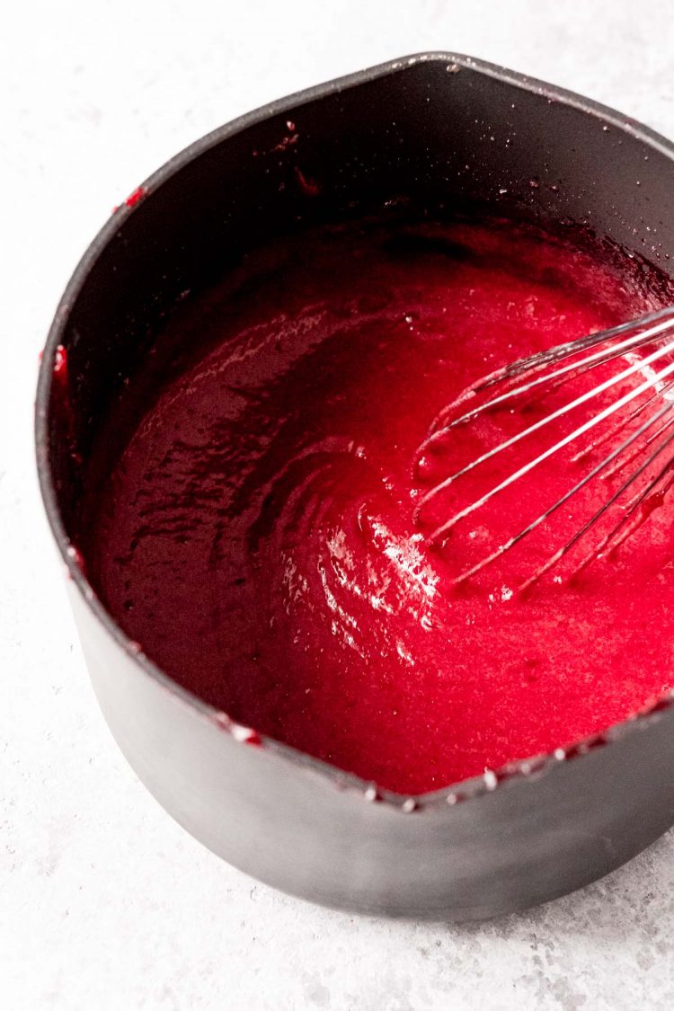 Cranberry curd in a medium saucepan with a whisk.