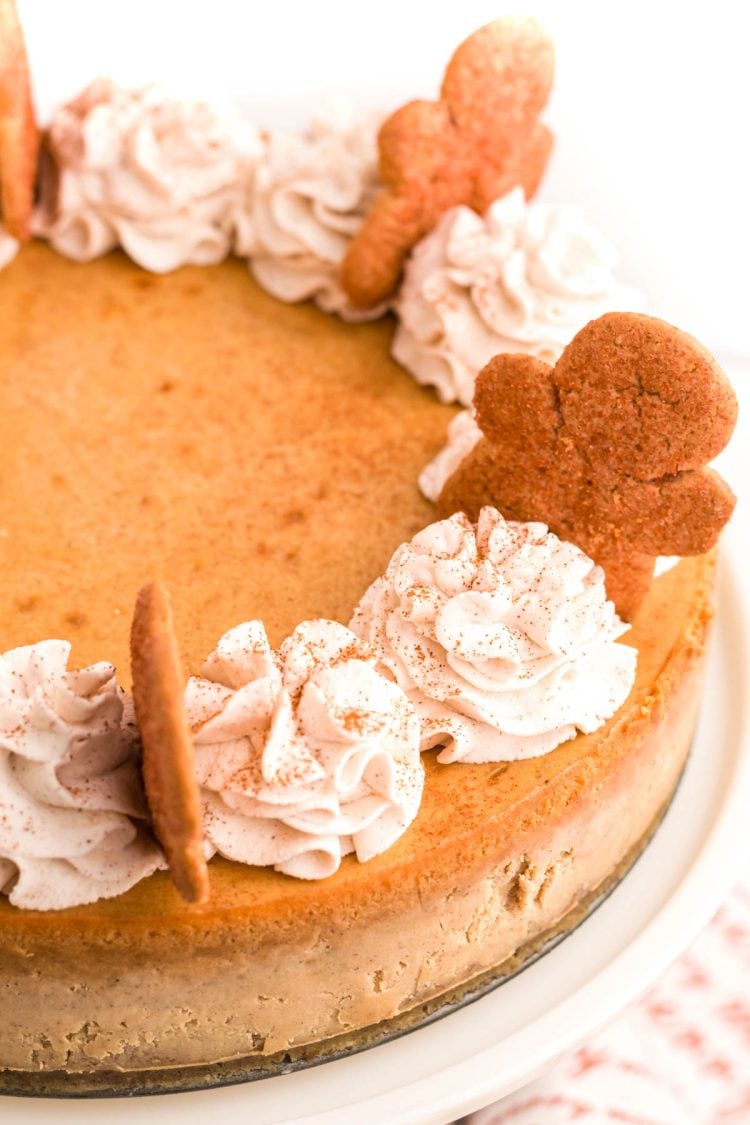 Close up photo of a gingerbread flavored cheesecake topped with whipped cream and gingerbread men.