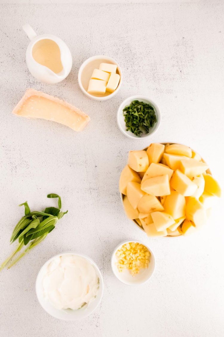 Overhead photo of ingredients to make mashed potatoes on a white surface.