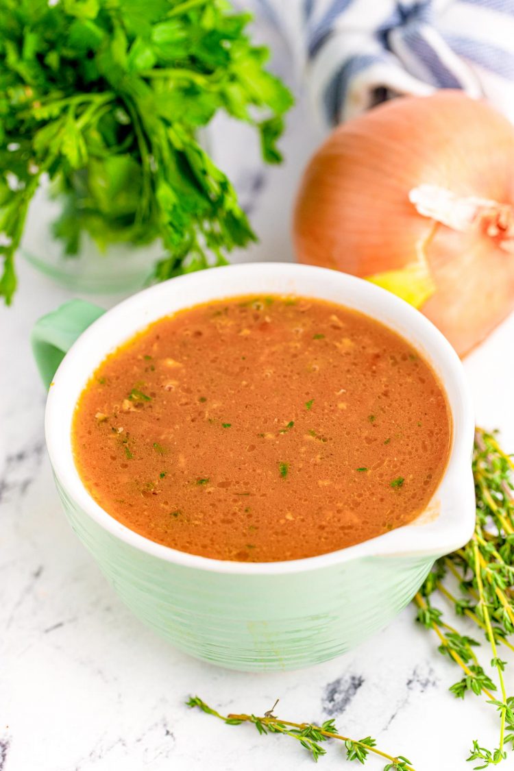 Onion gravy in a mint colored bowl with a pour spout.