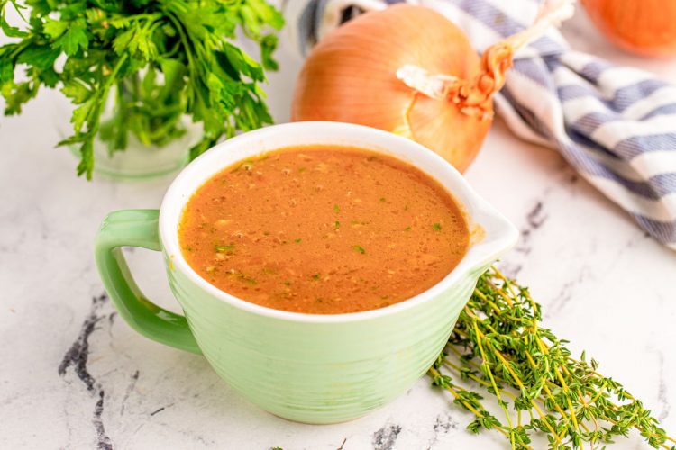 Onion gravy in a mint colored bowl with a pour spout.