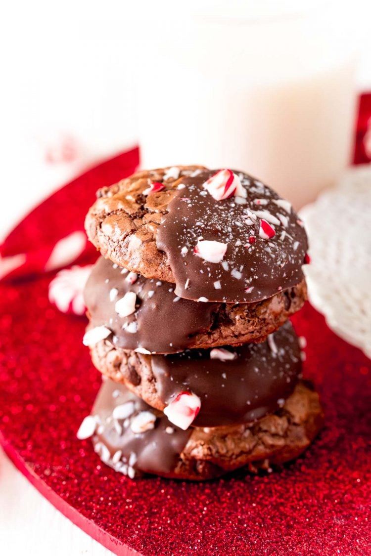 Stack of four peppermint brownie cookies on a red surface.