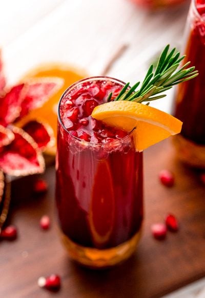 Close up photo of a pomegranate orange mimosa in a gold bottomed champagne glass.