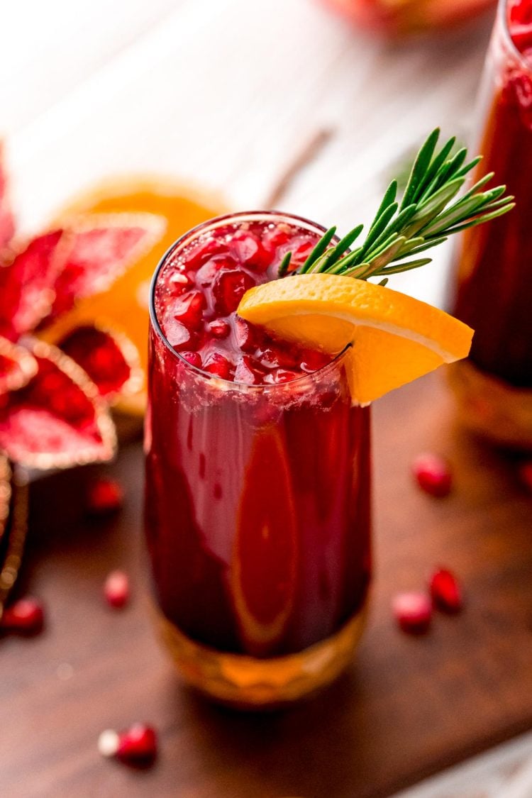 Close up photo of a pomegranate orange mimosa in a gold bottomed champagne glass.