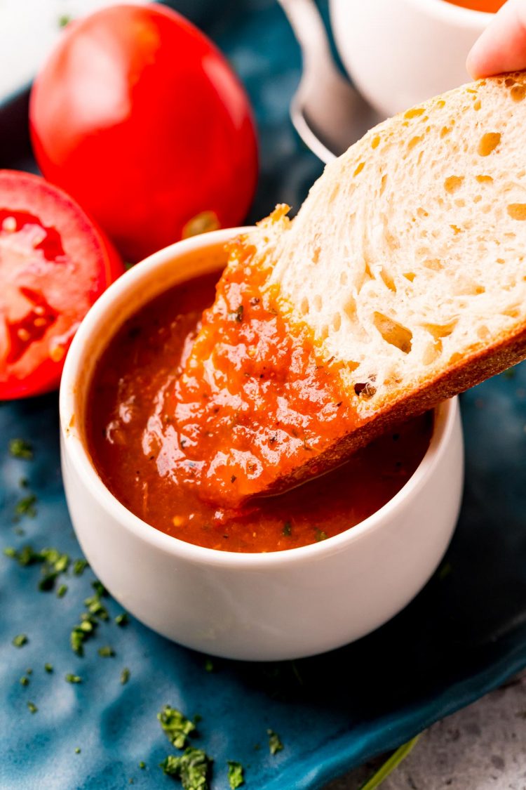 A slice of bread being dipped in tomato soup.
