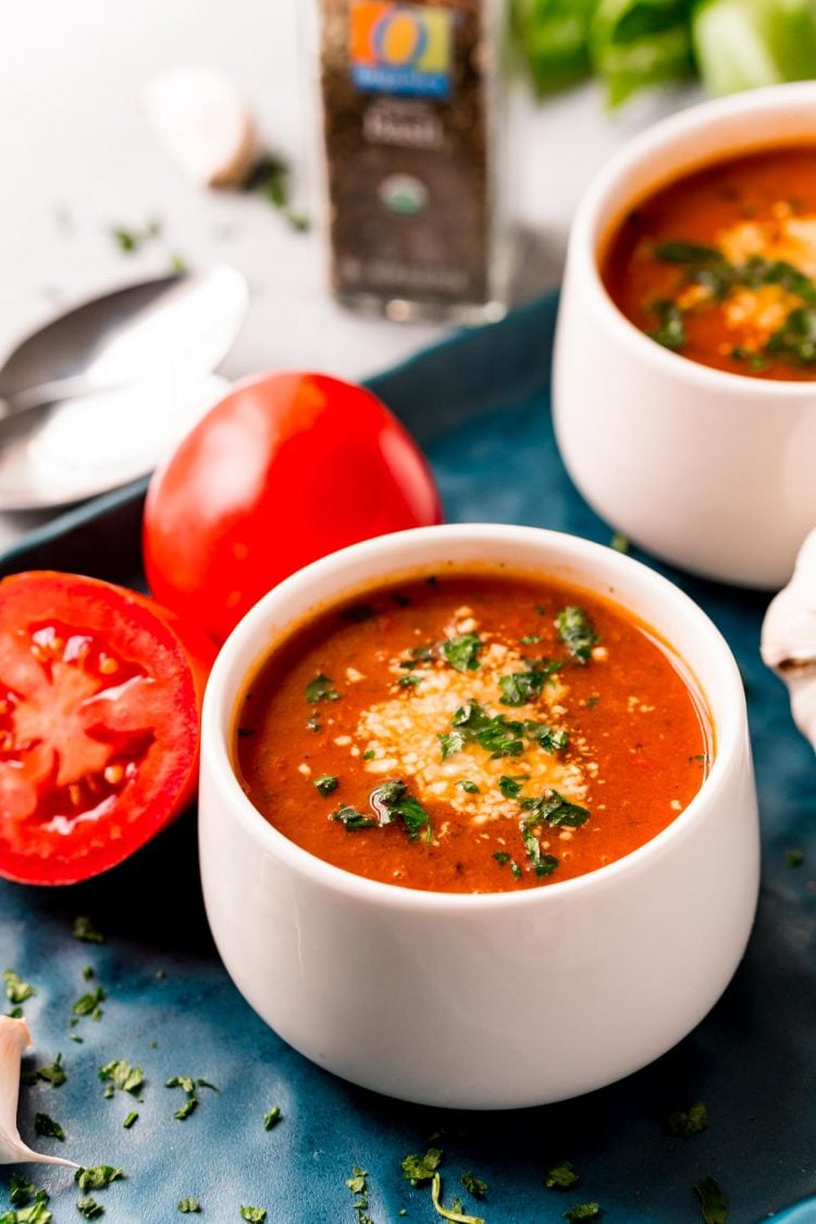 Tomato soup in a white bowl on a blue serving tray.