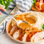 Onion gravy being spooned over a sliced turkey breast.