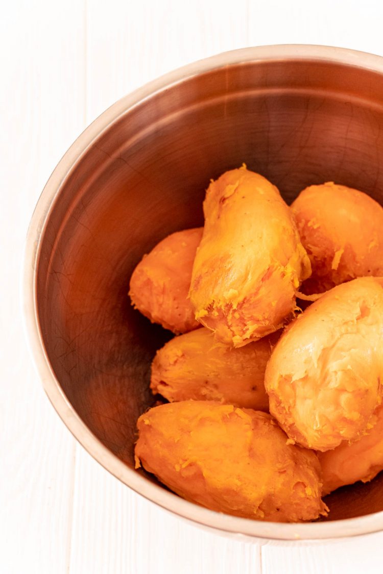Peeled cooked sweet potatoes in a metal mixing bowl.