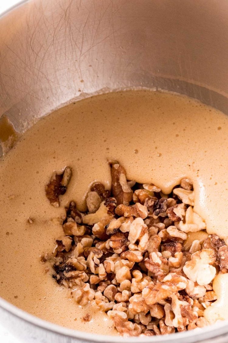 Walnuts being added to a mixing bowl with pie filling.