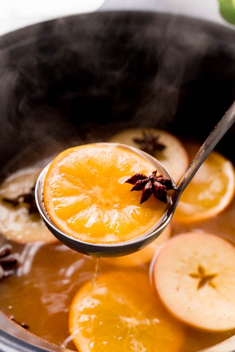 A ladle scooping wassail out of a crockpot.