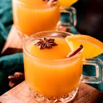 Close up photo of wassail in glass mugs garnished with cinnamon sticks and star anise.