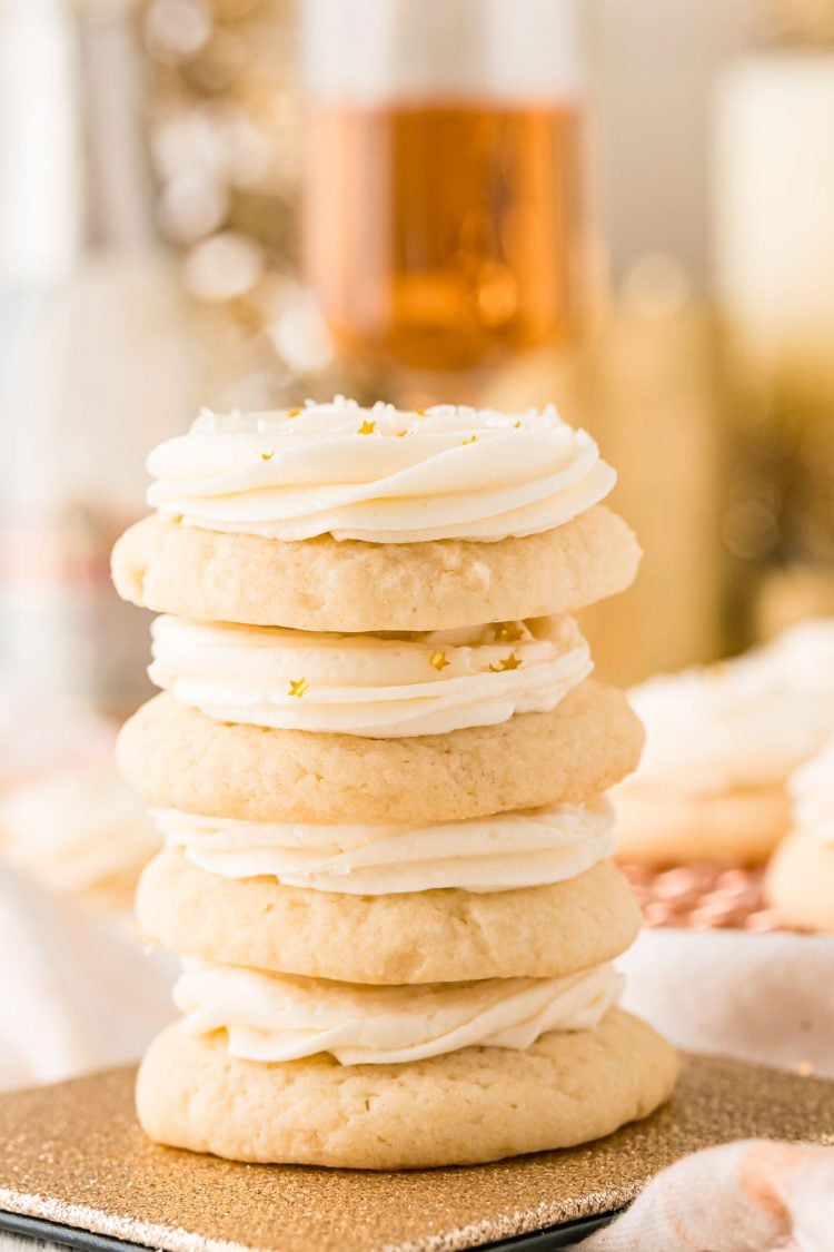 Close up photo of 4 sugar cookies stacked on top of each other with a glass of champagne in the background.