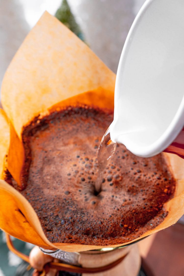 Hot water being poured over coffee in a pour over carafe.