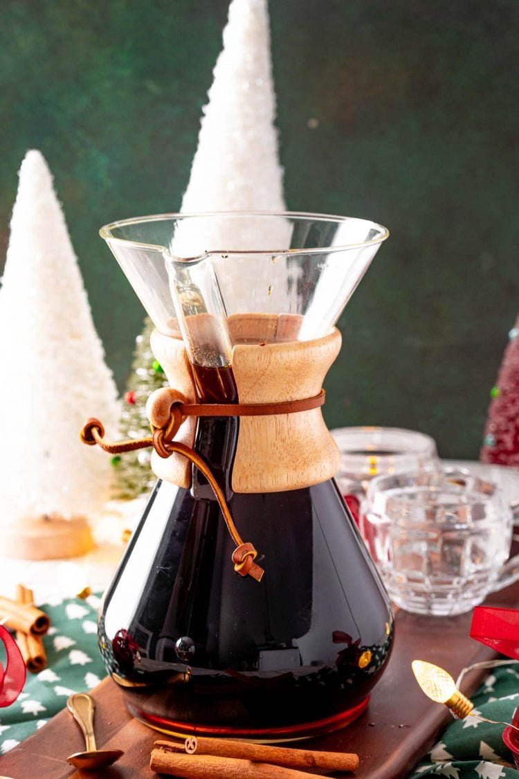 A carafe of coffee with Christmas decorations on the table.