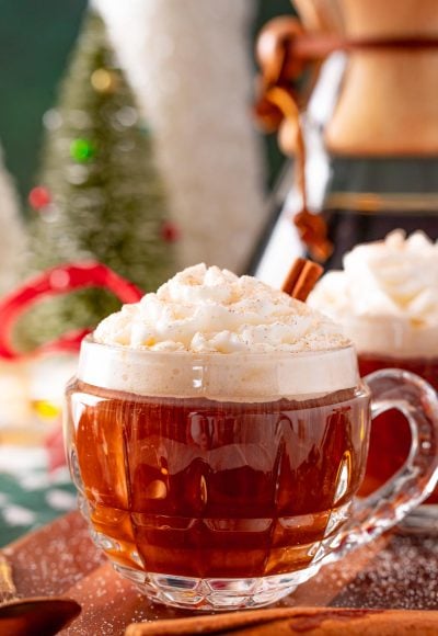 Close up photo of a mug of hot coffee topped with whipped cream at christmastime.