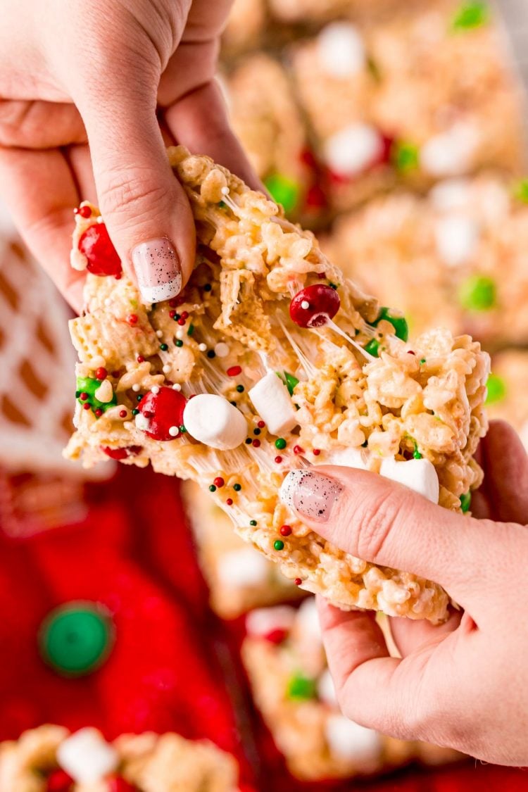 A woman's hand pulling apart a Christmas rice krispie treat.