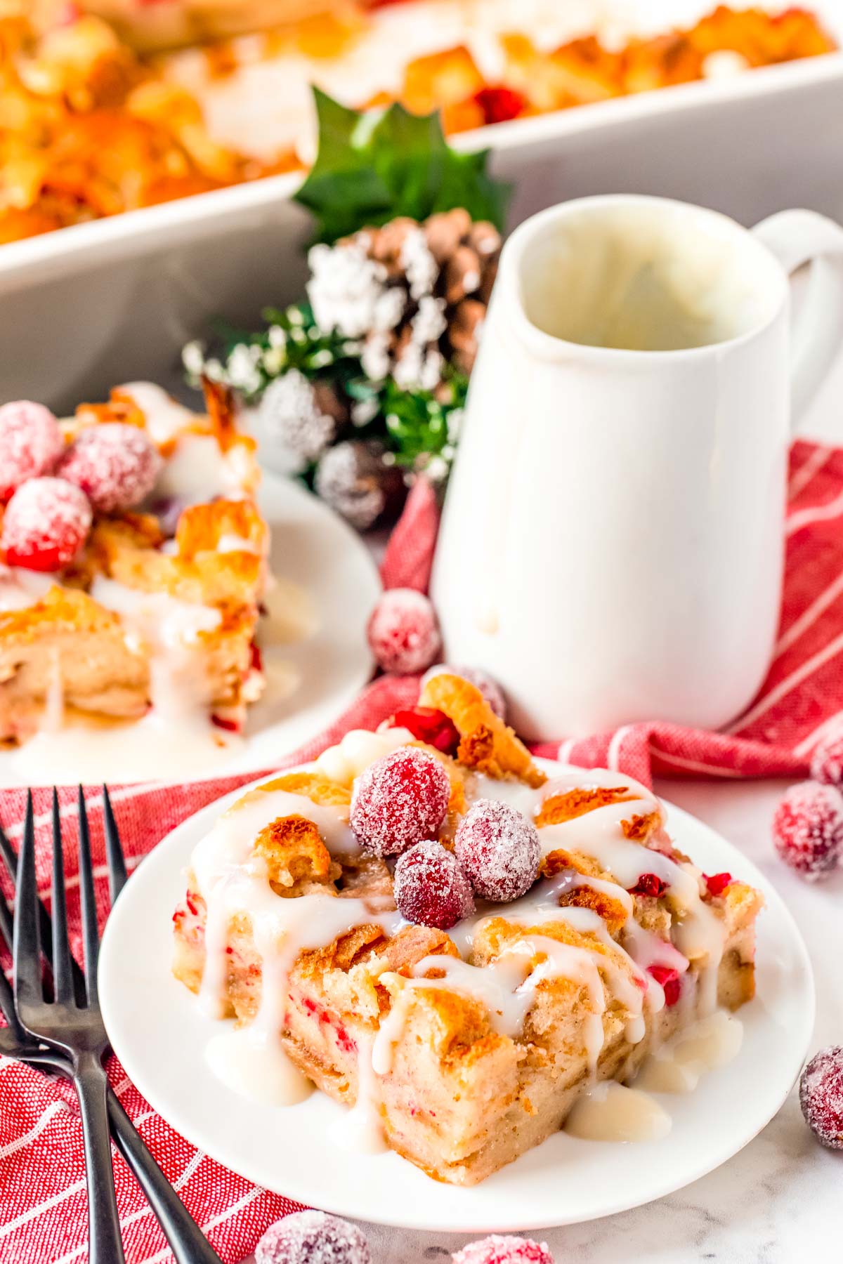 Close up photo of cranberry white chocolate bread pudding on a white plate.