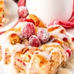 Close up photo of cranberry white chocolate bread pudding on a white plate.