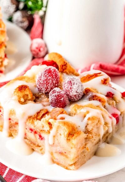 Close up photo of cranberry white chocolate bread pudding on a white plate.