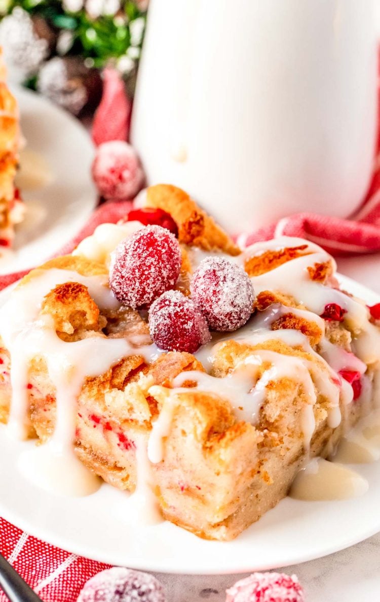 Close up photo of cranberry white chocolate bread pudding on a white plate.