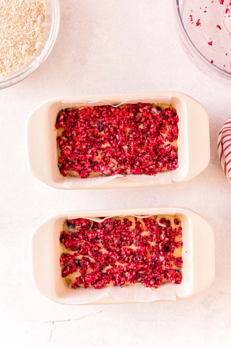 Overhead photo of two loaf pan with cranberry bits on top of the batter.