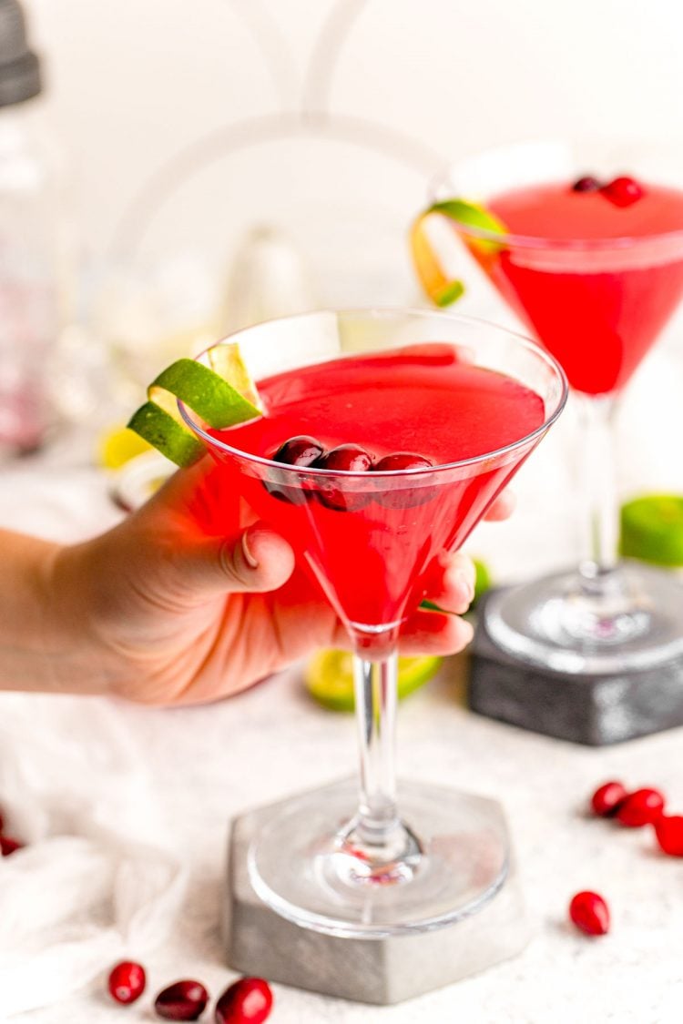 A woman's hand holding a cosmopolitan cocktail.