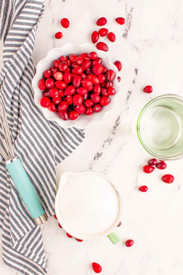 Overhead photo of ingredients to make cranberry simple syrup on a marble table.