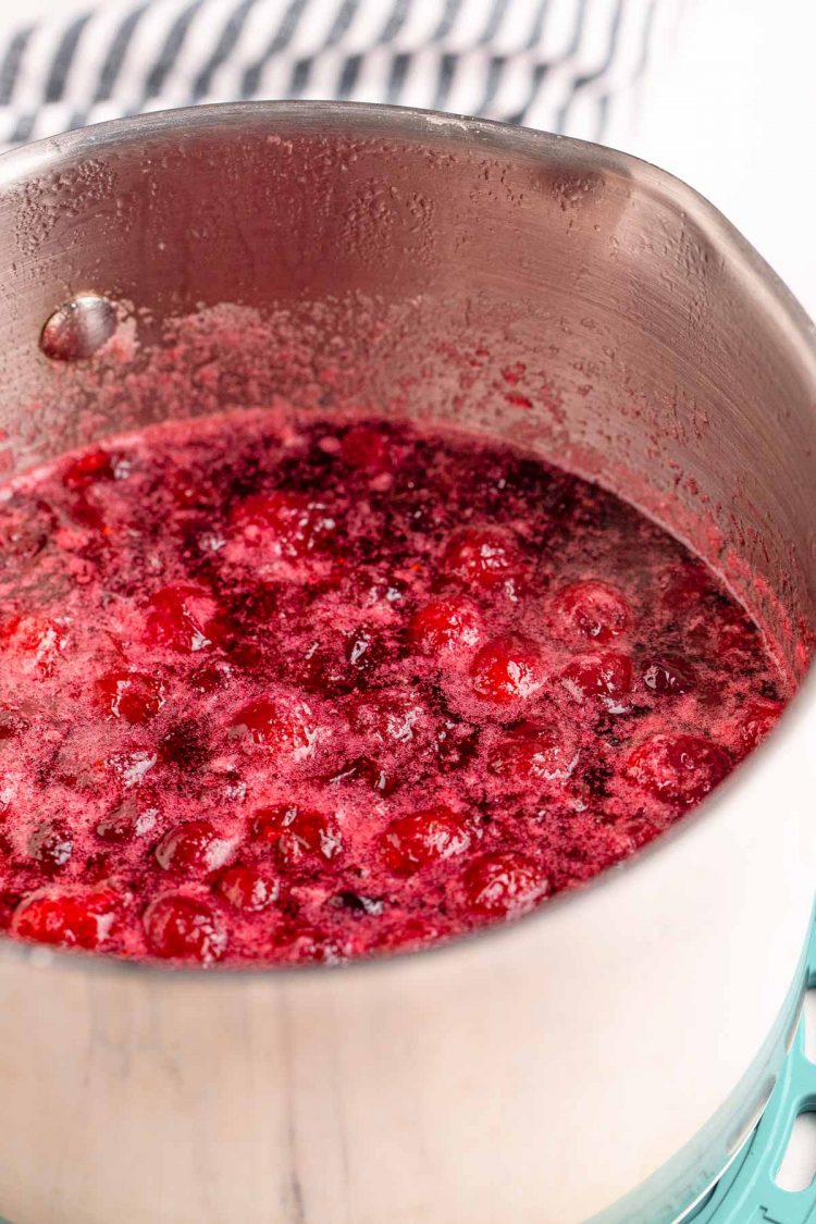 Cranberries simmering in a small saucepan.