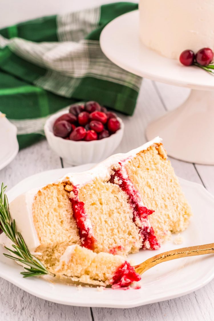 A slice of white cake with cranberry filling on a white plate.