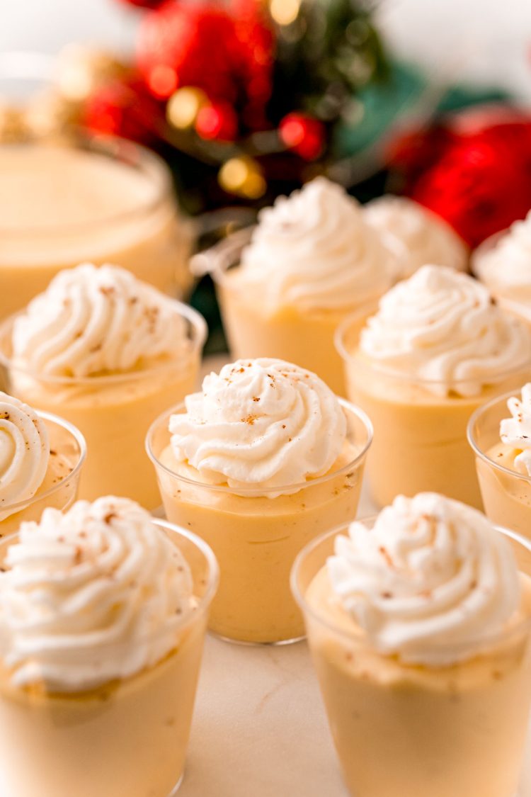Close up photo of pudding shots topped with whipped cream and nutmeg.