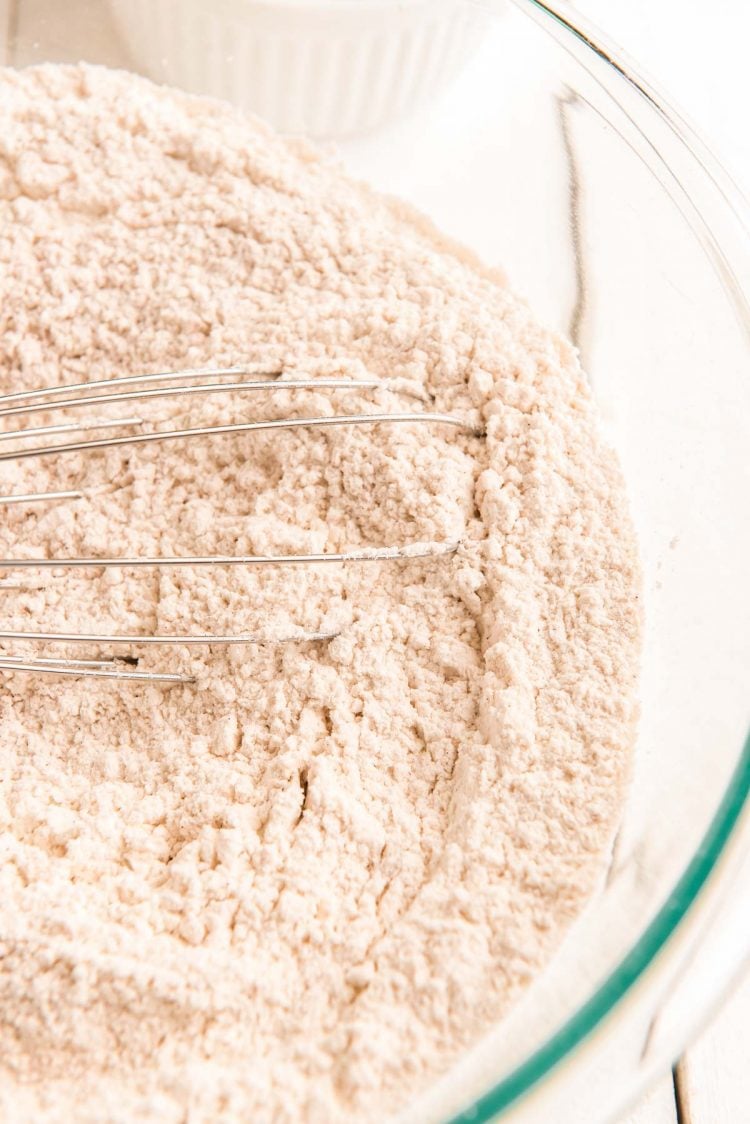 Flour and spices whisked together in a glass mixing bowl.