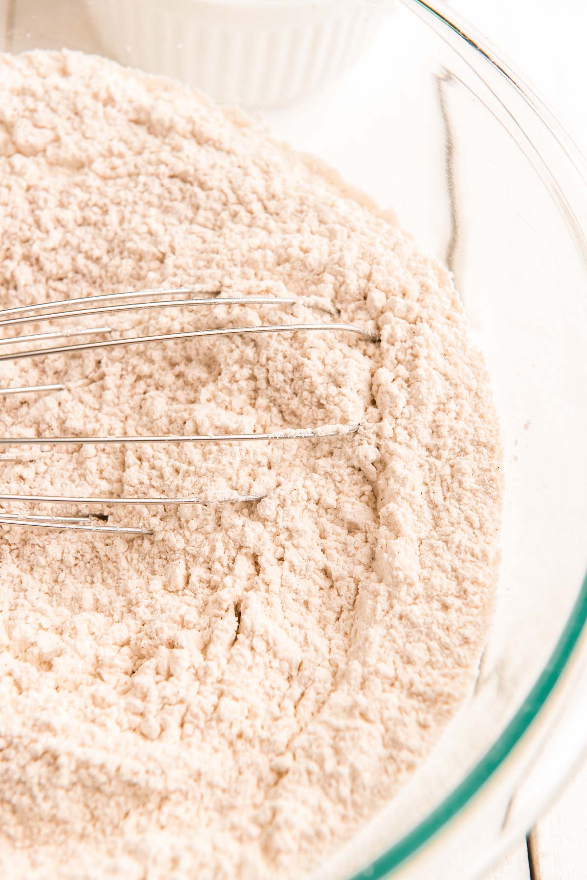 Flour and spices whisked together in a glass mixing bowl.