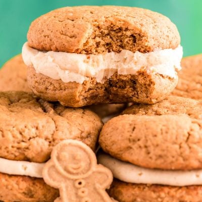 Close up photo of Gingerbread Whoopie pies stacking on eachother on a white plate with a bite taken out of one.