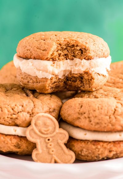 Close up photo of Gingerbread Whoopie pies stacking on eachother on a white plate with a bite taken out of one.