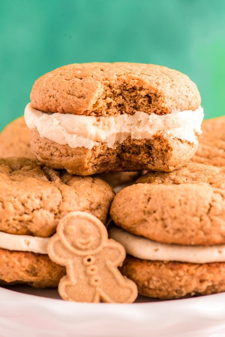 Close up photo of Gingerbread Whoopie pies stacking on eachother on a white plate with a bite taken out of one.