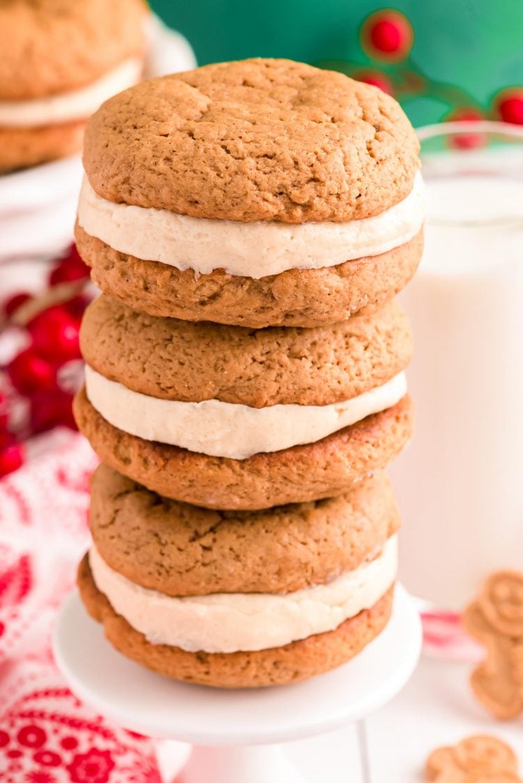 Three gingerbread whoopie pies stacked on top of each other on a small white cake stand.