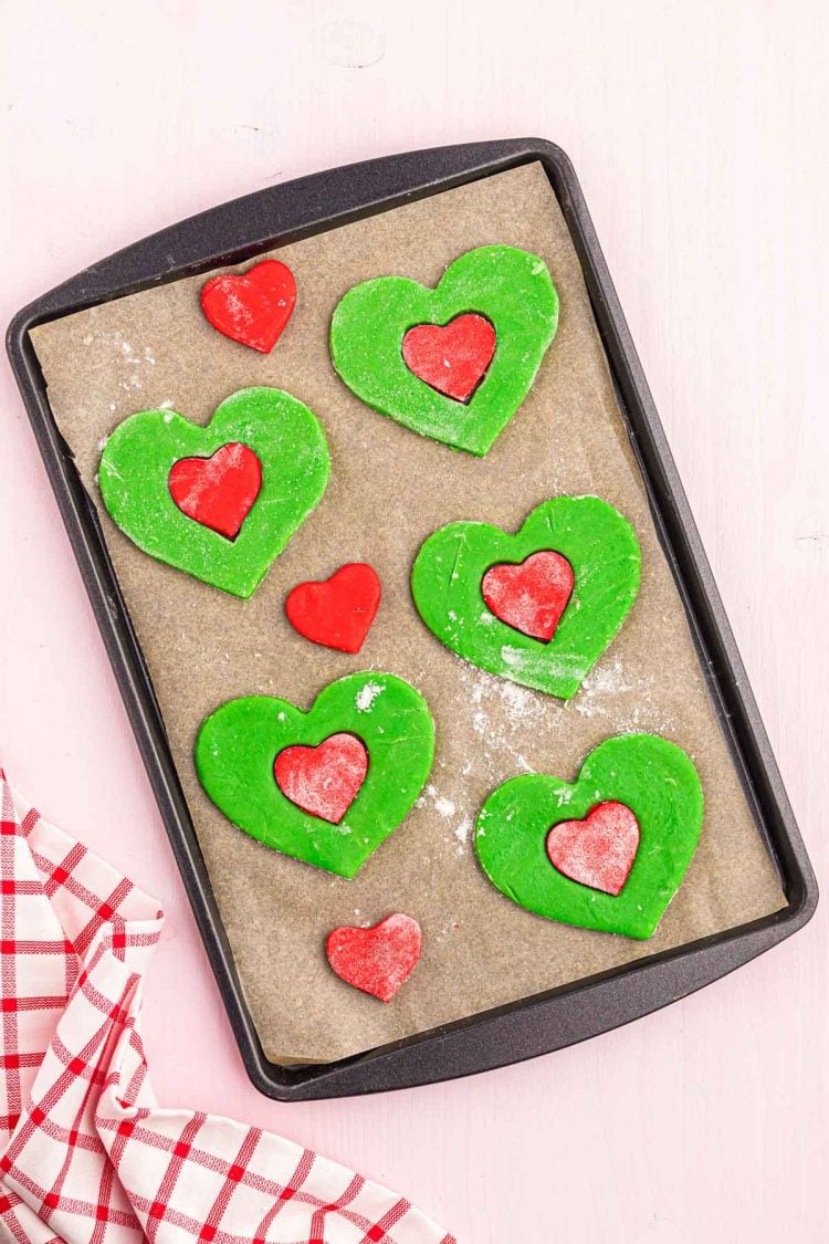 Grinch heart-shaped cookies on a baking sheet ready to bake.