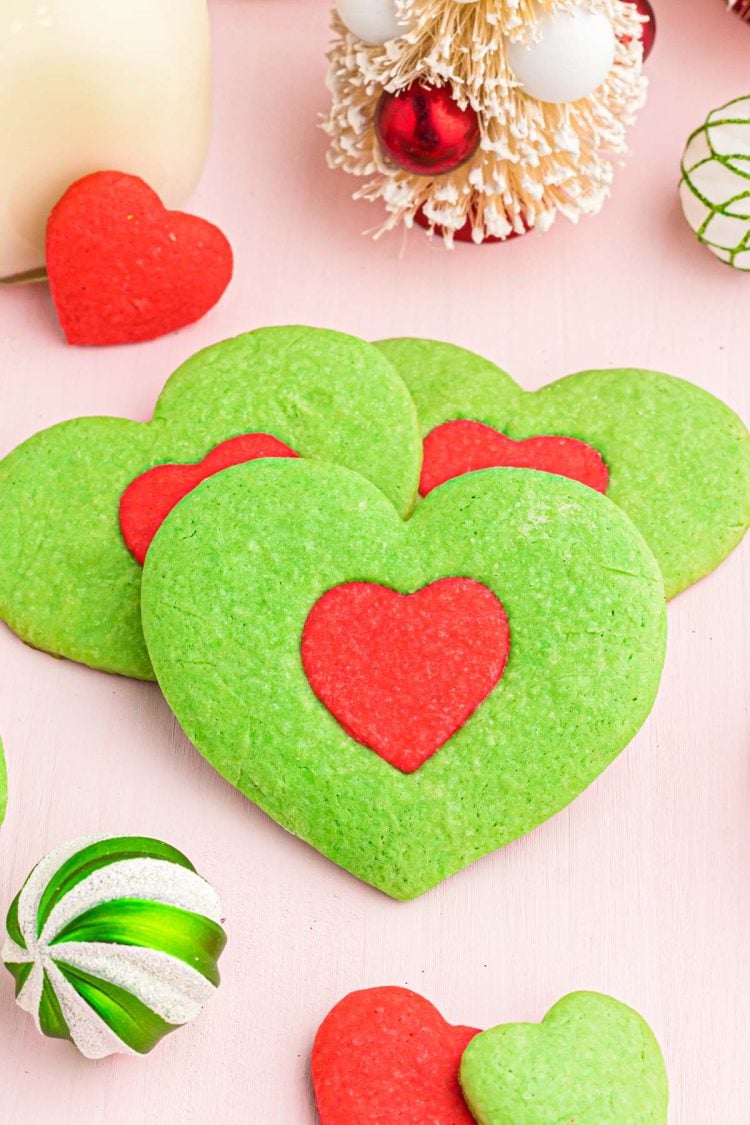 Close up photo of green heart shaped cookies with a red heart in the center inspired by the Grinch.