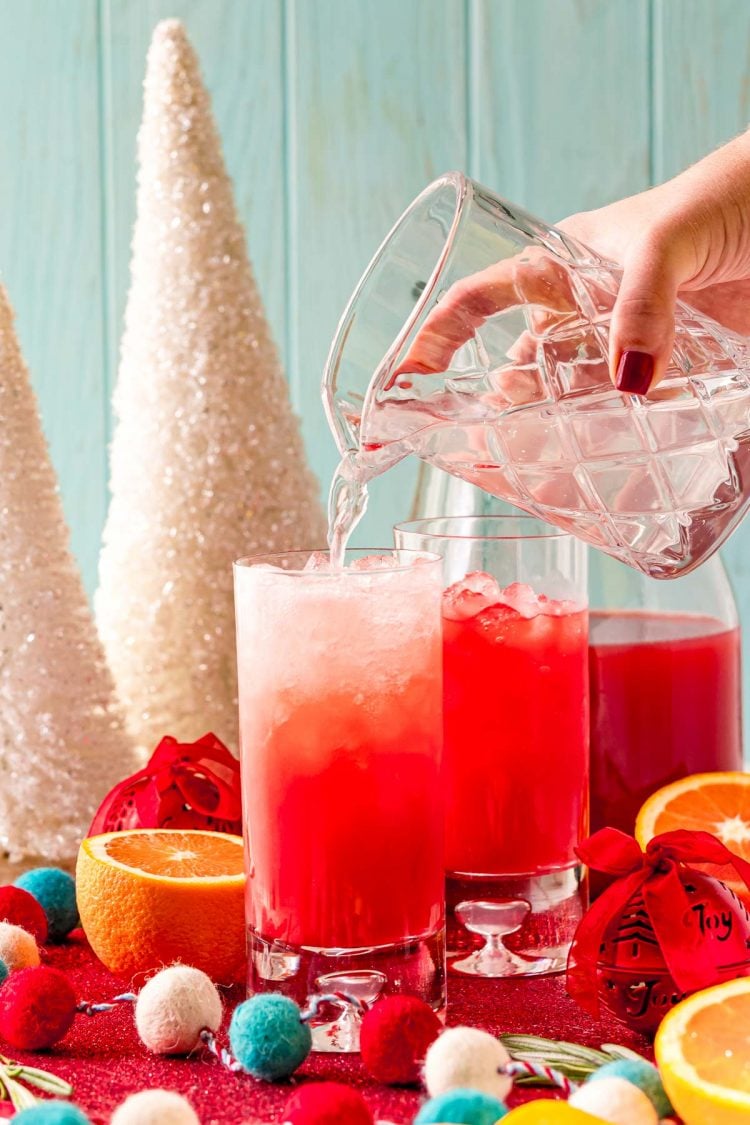 lemon-lime soda being poured into a glass filled with ice and red holiday punch.