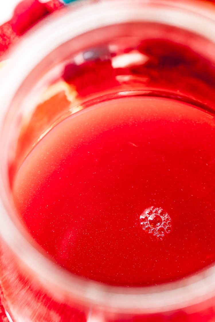 Close up photo of red punch in a glass carafe.