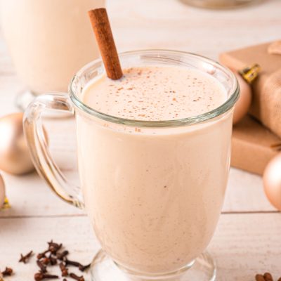 Close up photo of a mug of homemade eggnog on a light wooden counter.